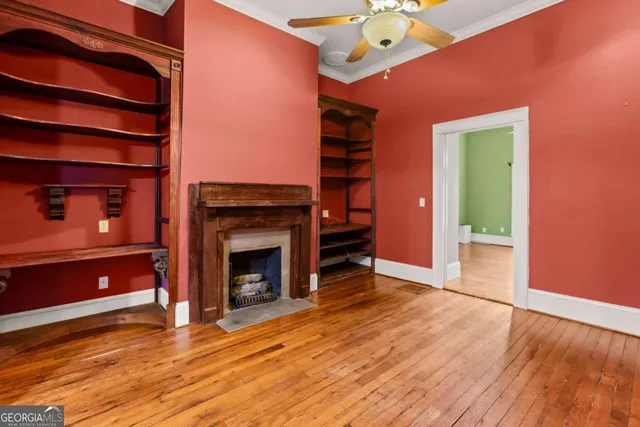 a view of an empty room with a window and wooden floor