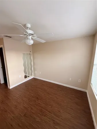 a view of an empty room with wooden floor and a window