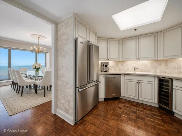 a kitchen with stainless steel appliances granite countertop a refrigerator a stove a sink and a dining table with wooden floor