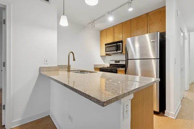 a kitchen with stainless steel appliances granite countertop a sink a refrigerator and a granite counter tops