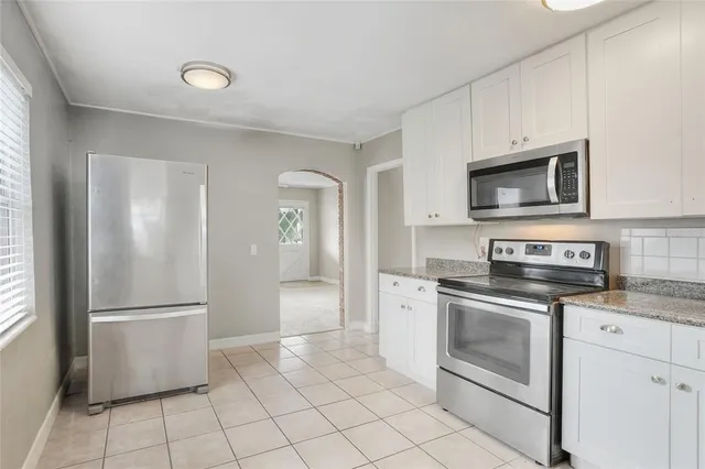 a kitchen with granite countertop white cabinets stainless steel appliances and a window