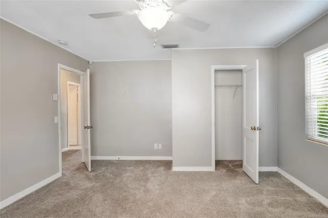 an empty room with windows and fan