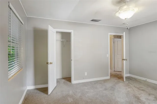 a view of an empty room with window and closet area