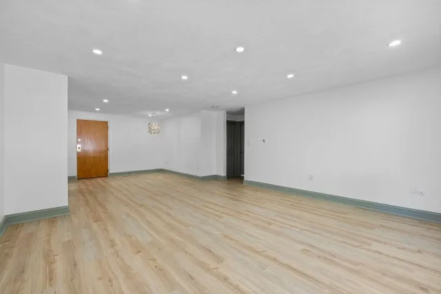 a view of an empty room with wooden floor and closet