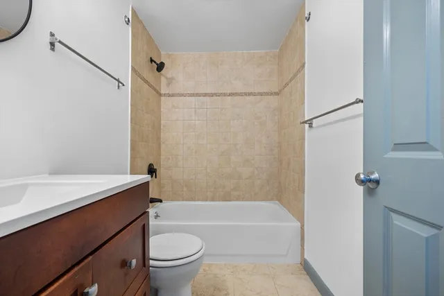 a bathroom with a granite countertop bathtub shower sink vanity and toilet