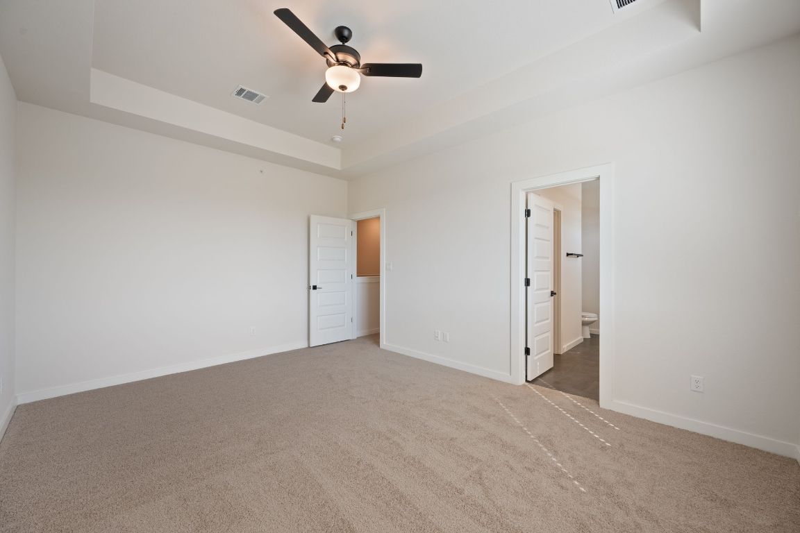 2600 Gattis School Road, Unit 1202 Round Rock, TX 78664 - Photo 12 of 24 Unfurnished bedroom with a tray ceiling, carpet floors, a ceiling fan, and connected bathroom