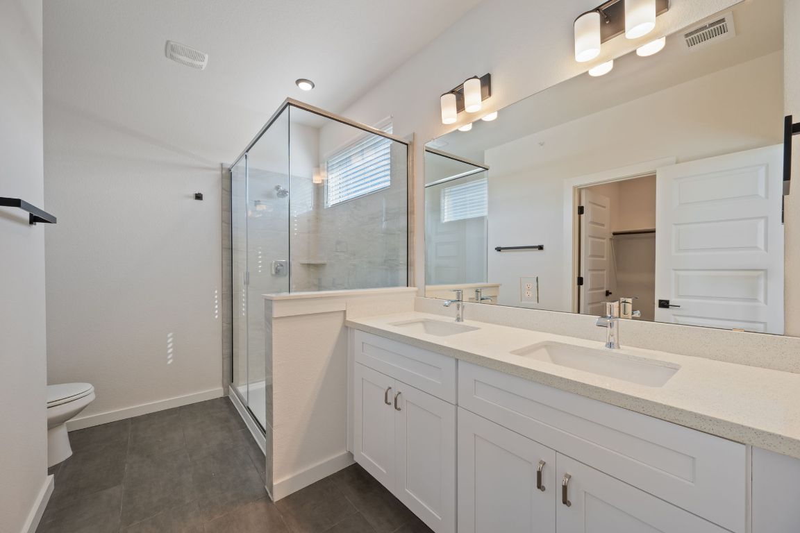 2600 Gattis School Road, Unit 1202 Round Rock, TX 78664 - Photo 13 of 24 Full bathroom with a stall shower, double vanity, a spacious closet, and dark tile patterned flooring