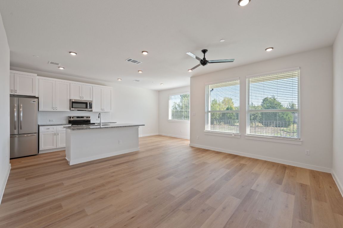 2600 Gattis School Road, Unit 1202 Round Rock, TX 78664 - Photo 22 of 24 Kitchen featuring stainless steel appliances, white cabinetry, a kitchen island with sink, open floor plan, and recessed lighting