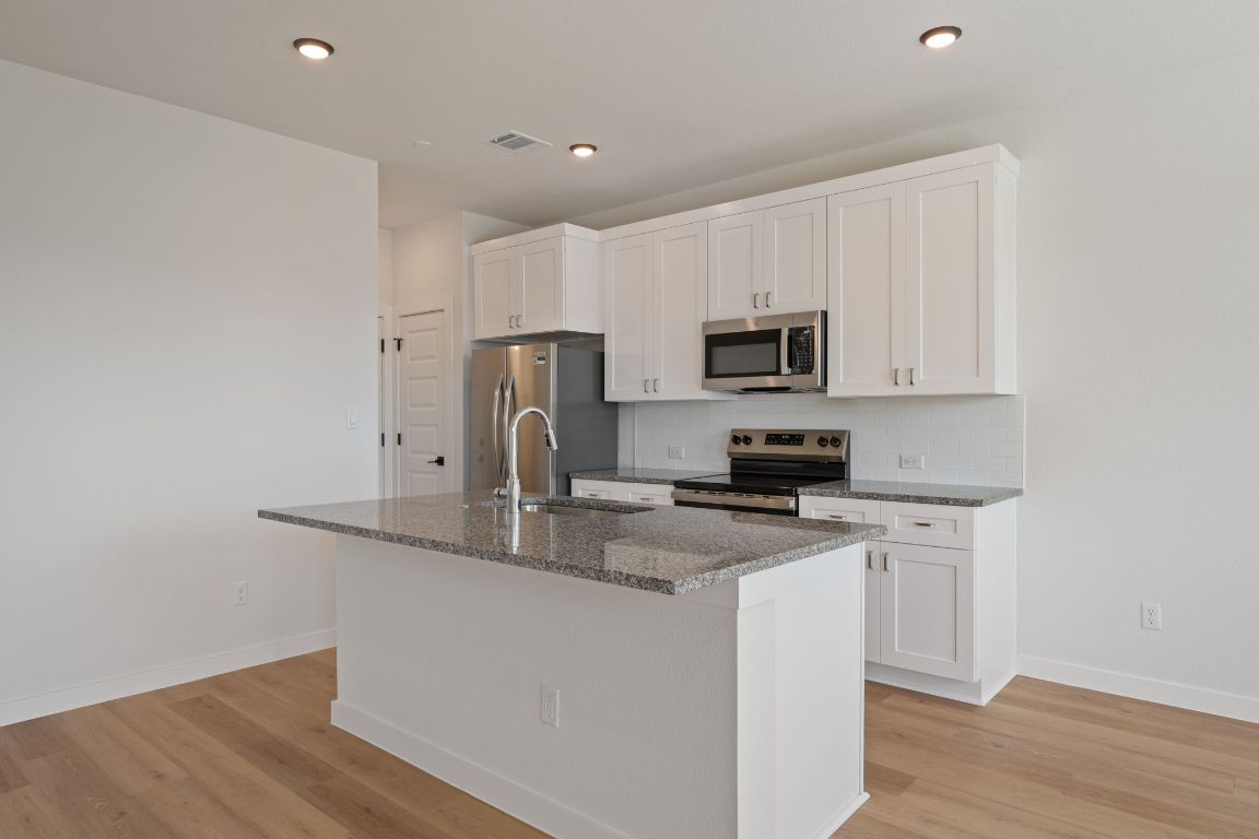 2600 Gattis School Road, Unit 1202 Round Rock, TX 78664 - Photo 7 of 24 Kitchen featuring white cabinets, dark stone counters, stainless steel appliances, light wood finished floors, and recessed lighting