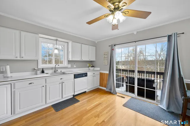 a kitchen with granite countertop a stove a sink and white cabinets with wooden floor next to windows