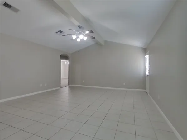 an empty room with chandelier fan and windows