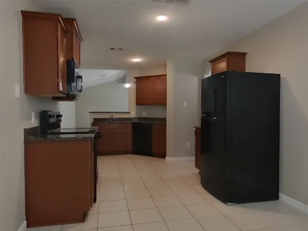 a kitchen with stainless steel appliances granite countertop a refrigerator and a wooden floors