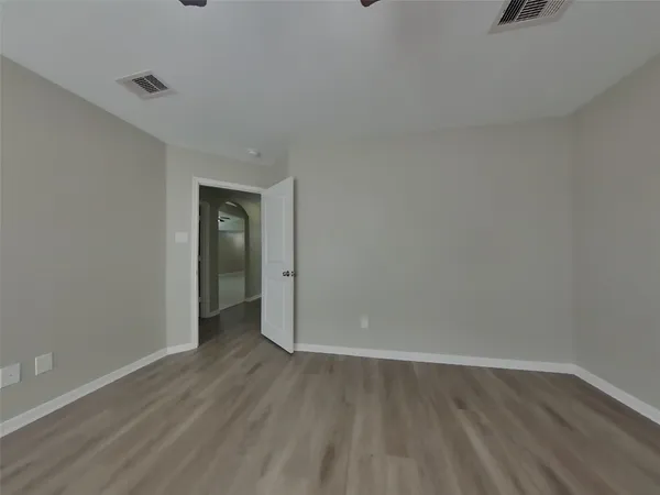 a view of an empty room with wooden floor and closet