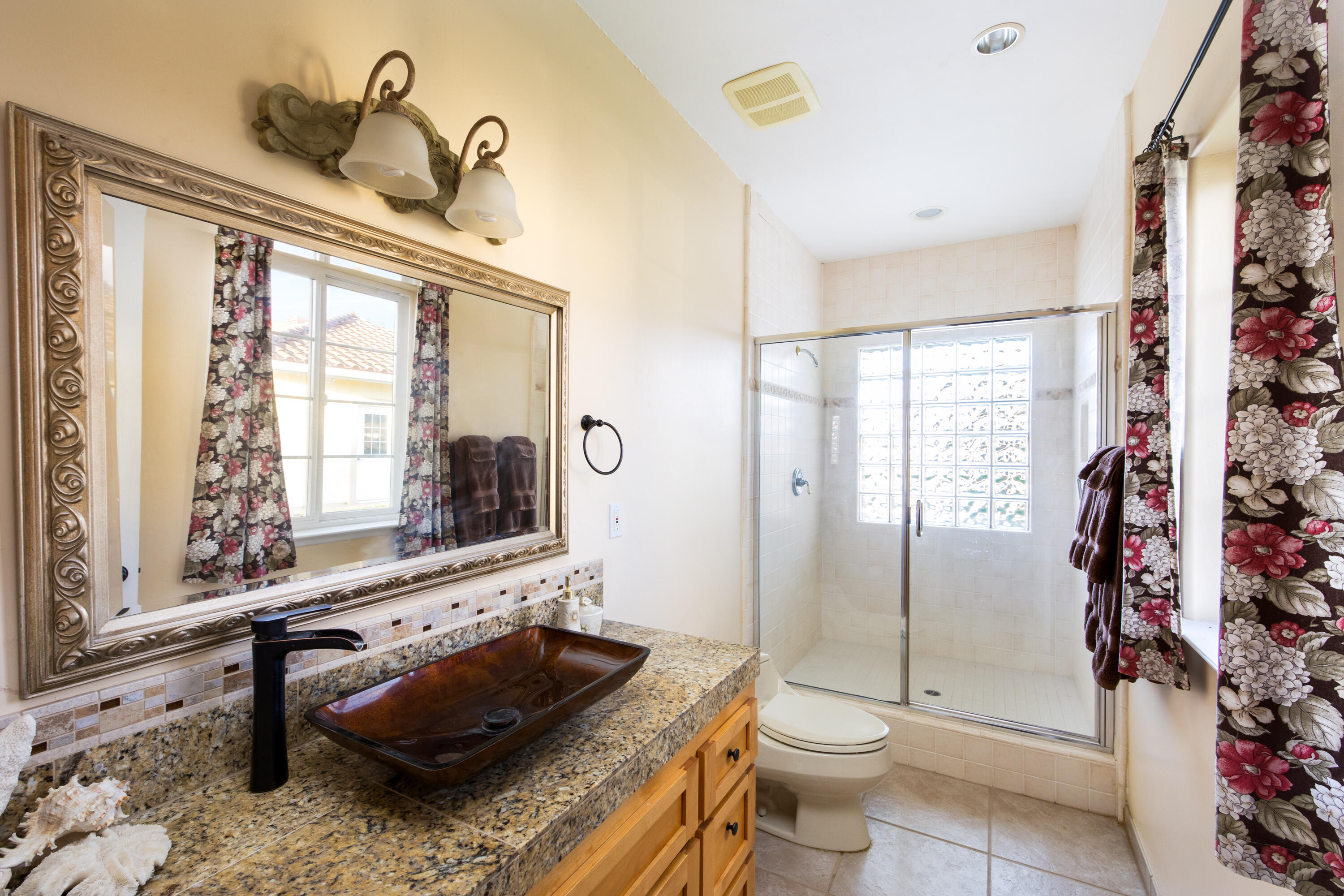 7253 Santos Road Lompoc, CA 93436 - Photo 16 of 28 a bathroom with a granite countertop sink a toilet a mirror and shower