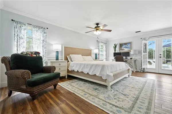 a bedroom with a large bed a chandelier and windows