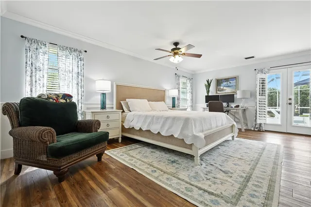 a bedroom with a large bed a chandelier and windows