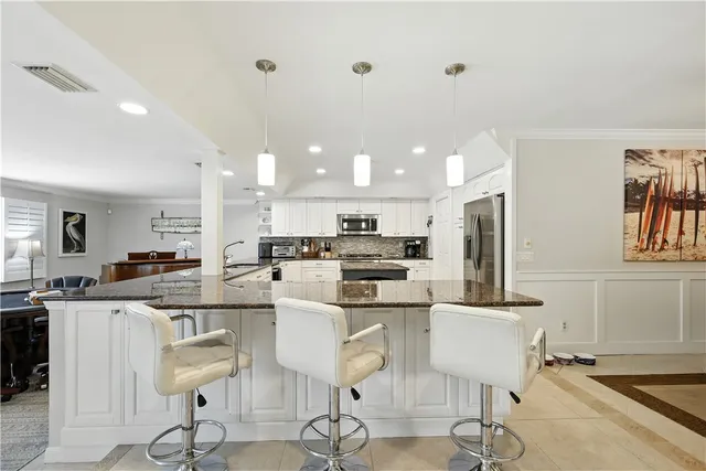 a dining room with stainless steel appliances kitchen island granite countertop a dining table and chairs