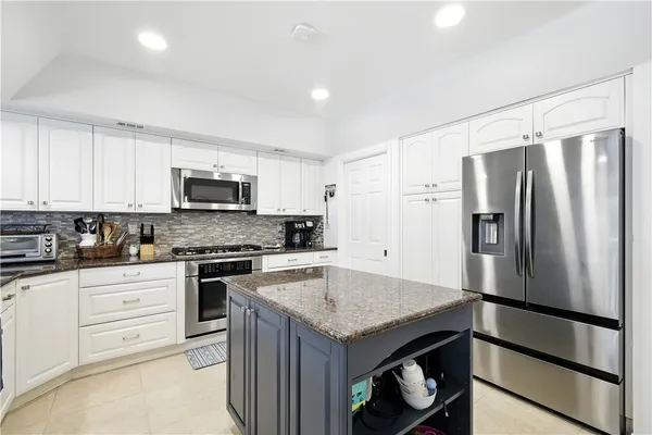 a kitchen with white cabinets and stainless steel appliances