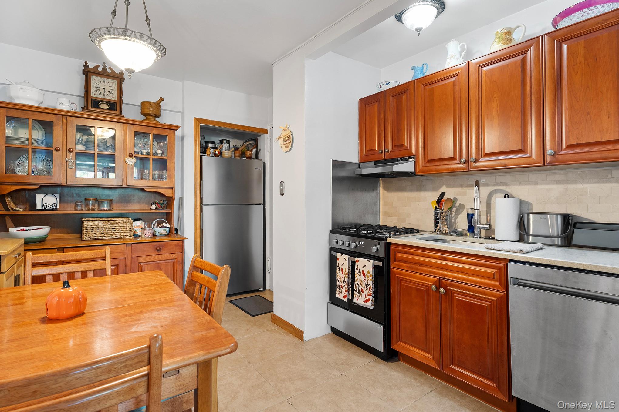 9040 Fort Hamilton Parkway, Unit 3 Brooklyn, NY 11209 - Photo 5 of 11 Kitchen with appliances with stainless steel finishes, glass insert cabinets, backsplash, and brown cabinetry