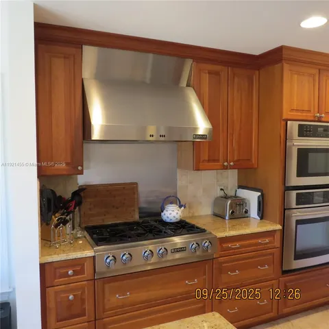 a kitchen with granite countertop a stove oven and white cabinets