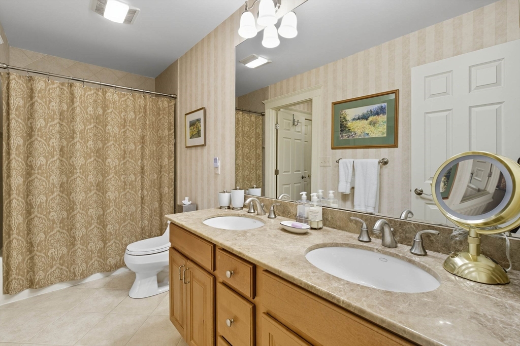3 Warren Drive Middleton, MA 01949 - Photo 34 of 42 a bathroom with double vanity sinks a toilet a mirror and shower curtain