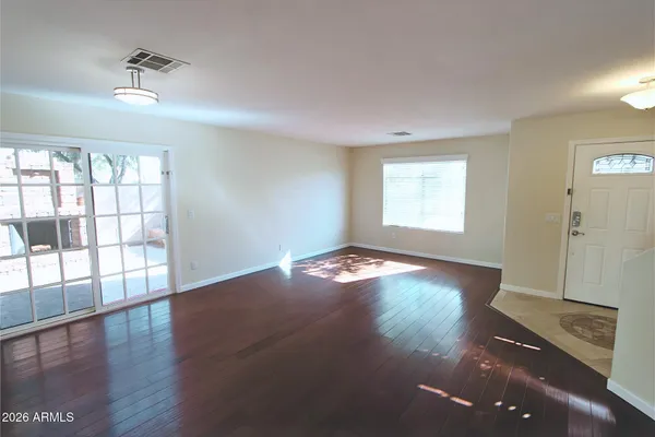 an empty room with wooden floor and windows