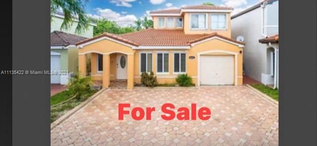 a view of a white house with a small yard and potted plants