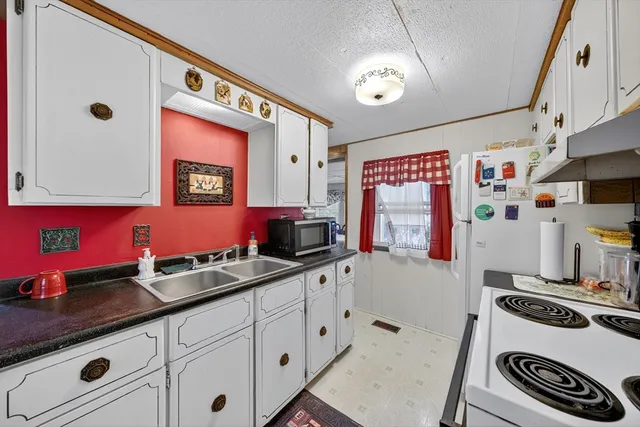 a kitchen with granite countertop a sink stove and cabinets