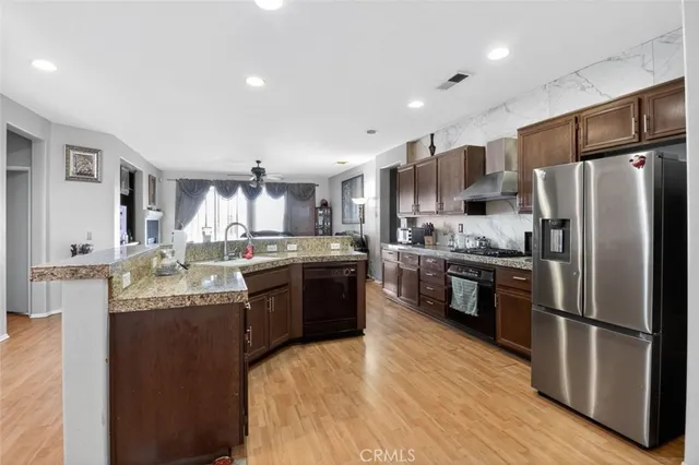 a kitchen with stainless steel appliances granite countertop a refrigerator a stove a sink dishwasher a oven with white cabinets and wooden floor