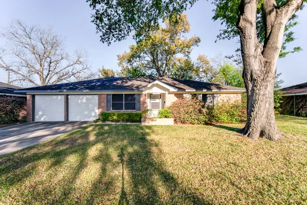 a view of a house with a large tree and a yard