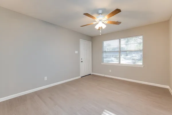 an empty room with window and chandelier fan