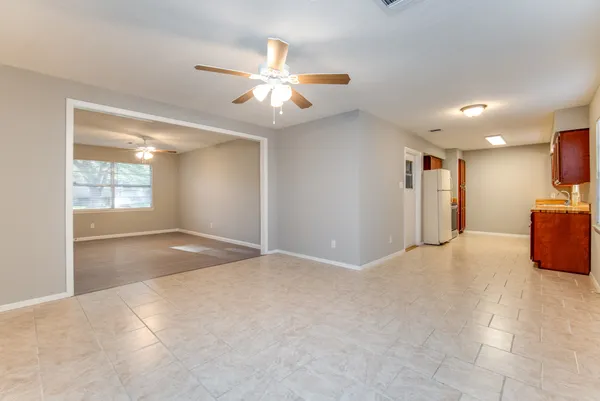 a view of an empty room with window and chandelier fan