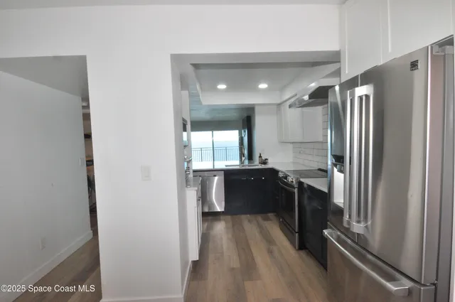 a large white kitchen with kitchen island a sink stainless steel appliances and cabinets
