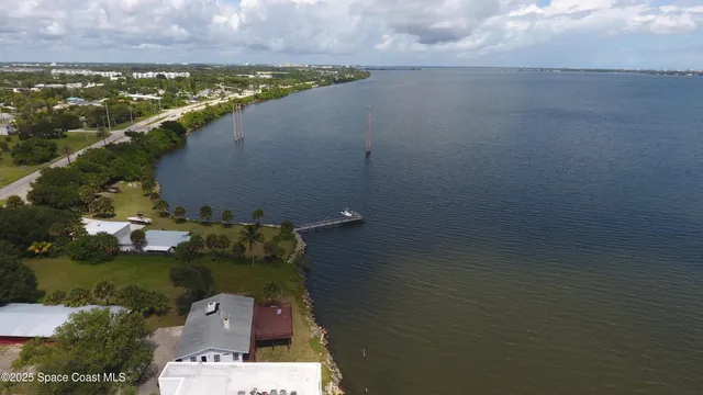 an aerial view of ocean and residential houses with outdoor space