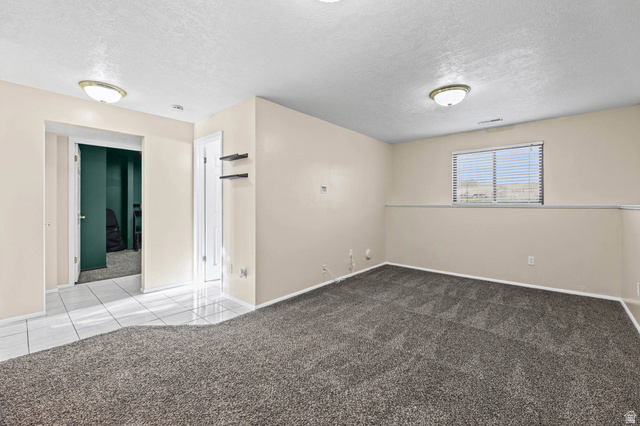 5896 South 3950th Street West Roy, UT 84067 - Photo 17 of 29 Tiled empty room featuring carpet flooring and a textured ceiling