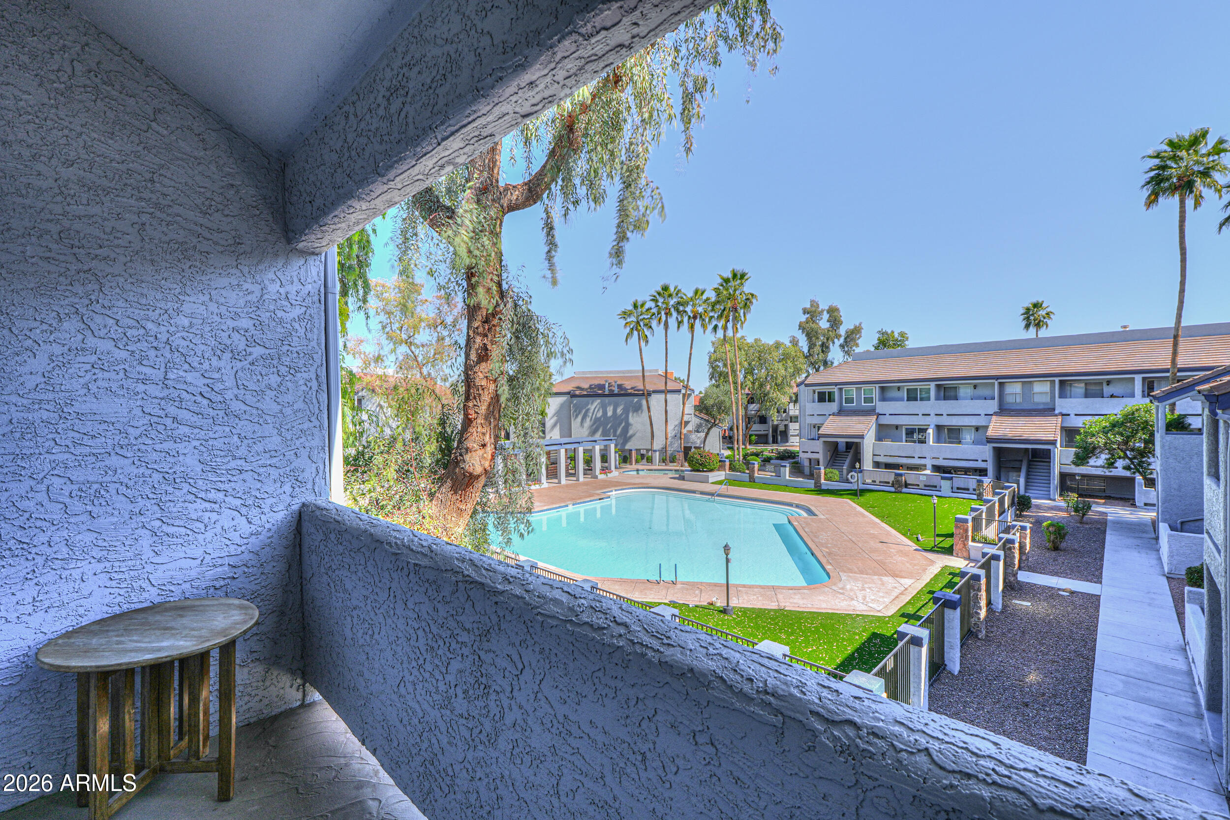 view of a pool with lawn chairs and potted plants