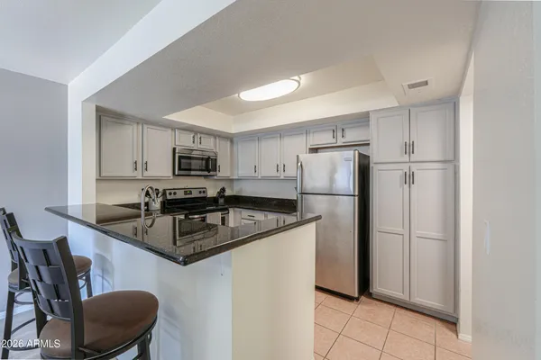 a kitchen with stainless steel appliances granite countertop a refrigerator a stove a sink a microwave and a refrigerator