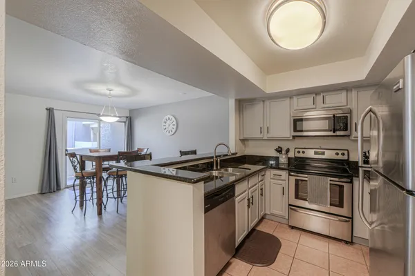 a kitchen with stainless steel appliances granite countertop a stove top oven a sink dishwasher a dining table and chairs with wooden floor