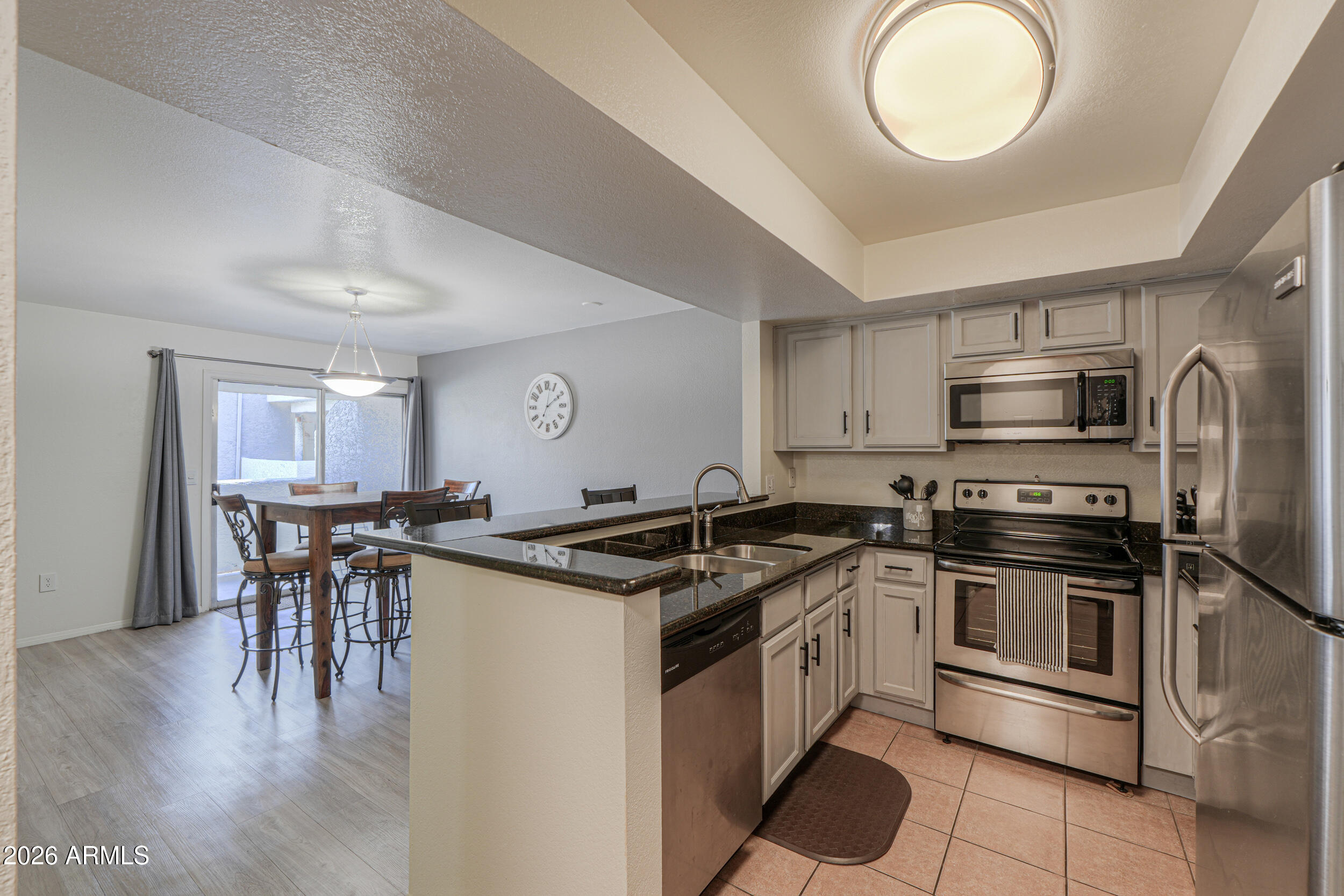 1331 West Baseline Road, Unit 225 Mesa, AZ 85202 - Photo 13 of 47 a kitchen with stainless steel appliances granite countertop a stove top oven a sink dishwasher a dining table and chairs with wooden floor