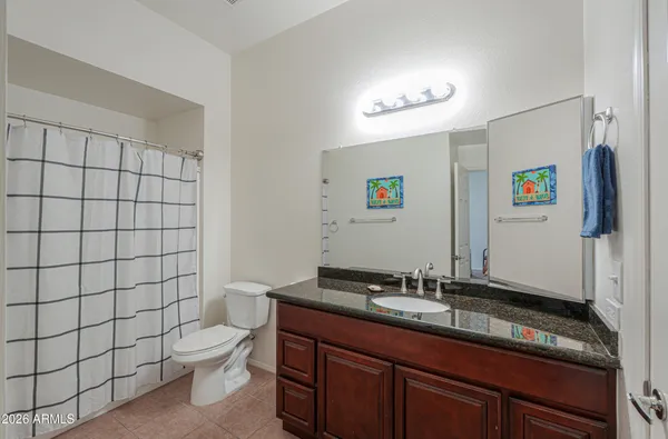 a bathroom with a granite countertop sink a toilet and a shower curtain
