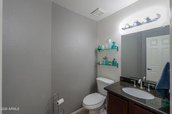 a bathroom with a granite countertop toilet a sink and a mirror
