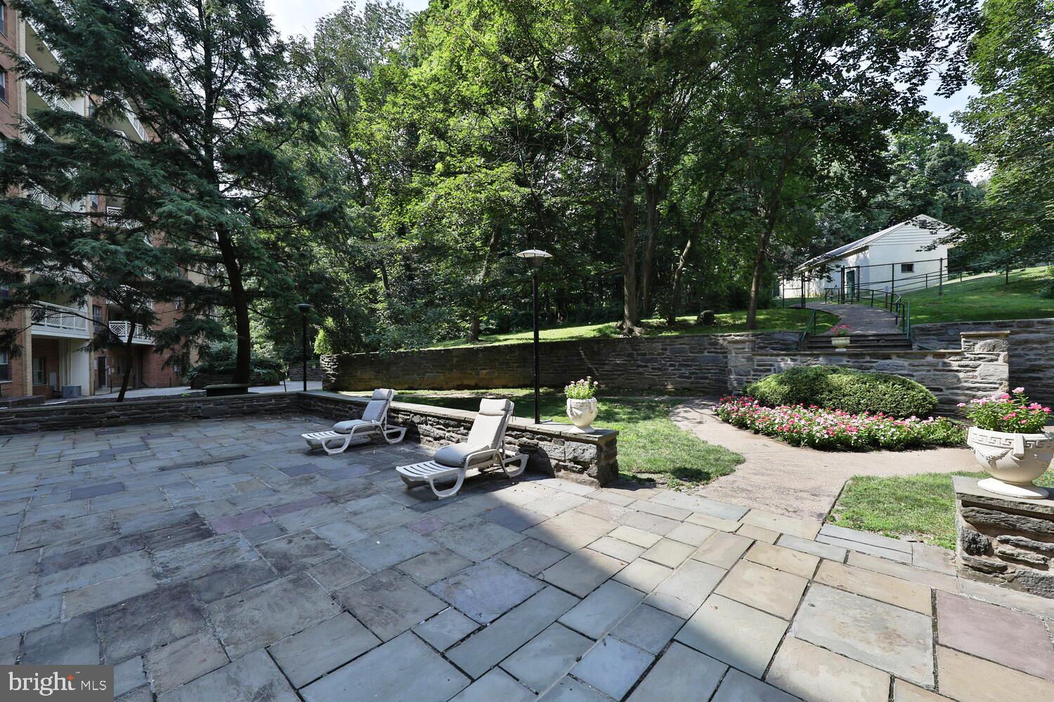 7900 Old York Road, Unit 907A Elkins Park, PA 19027 - Photo 31 of 36 a view of a backyard with table and chairs potted plants and large tree