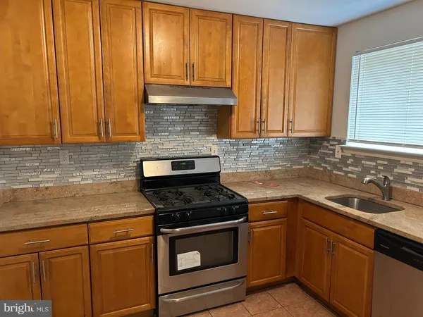 a kitchen with granite countertop wood cabinets stainless steel appliances and a sink