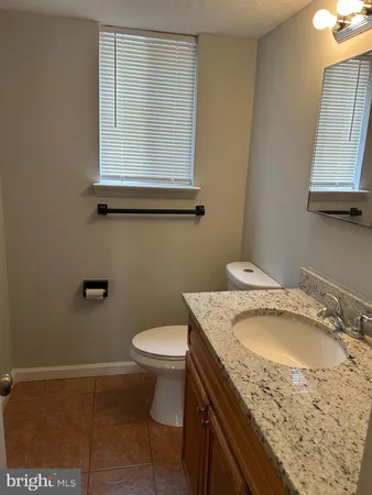 a bathroom with a granite countertop sink toilet and mirror
