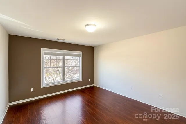 an empty room with wooden floor and window
