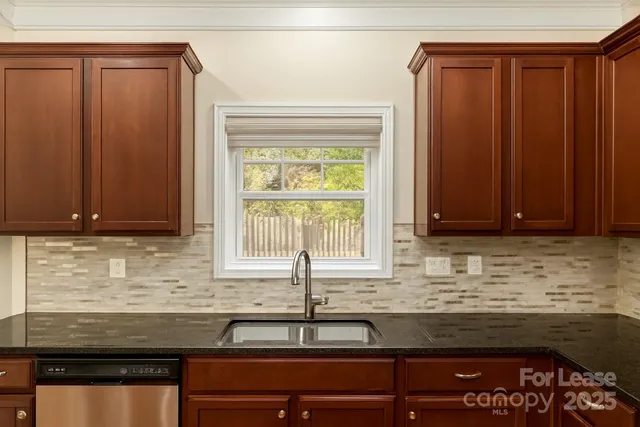 a kitchen with granite countertop wooden cabinets a sink and a window