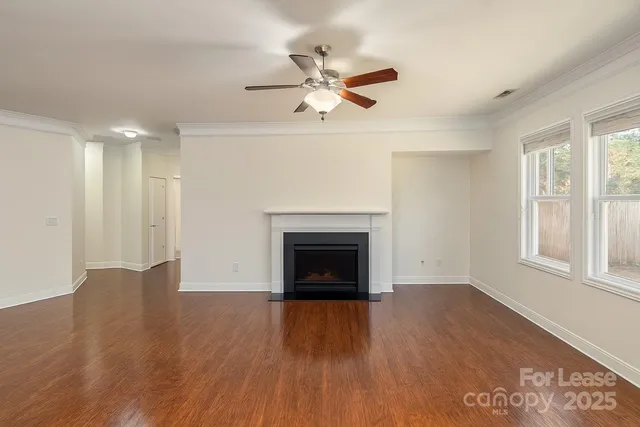 an empty room with wooden floor fireplace and windows