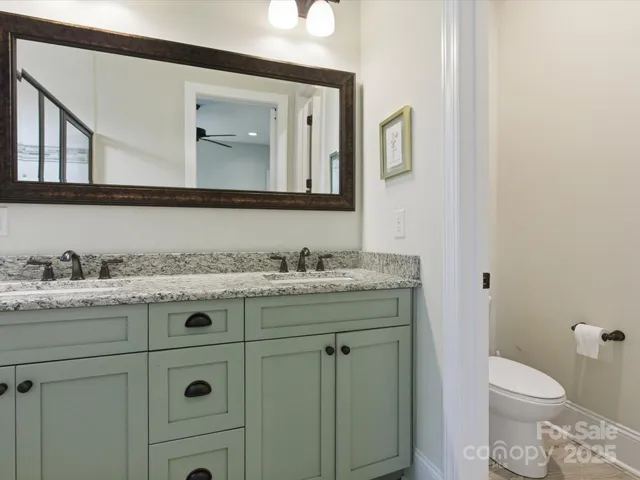 a bathroom with a granite countertop toilet sink and mirror