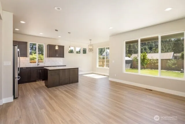 a large room with kitchen island wooden floors and stainless steel appliances