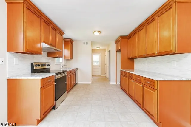 a large kitchen with stainless steel appliances granite countertop a stove a sink and a refrigerator